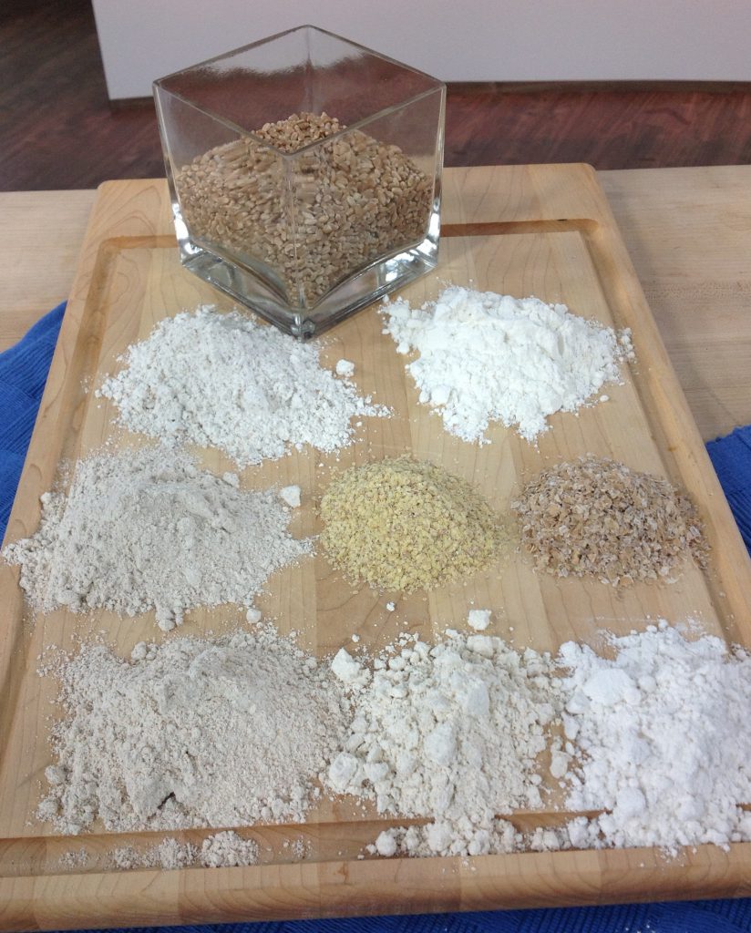 types of wheat and flour on a wooden board