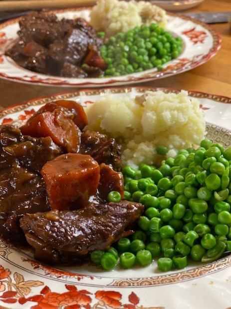 a rich and hearty beef stew served with mashed potatoes and peas