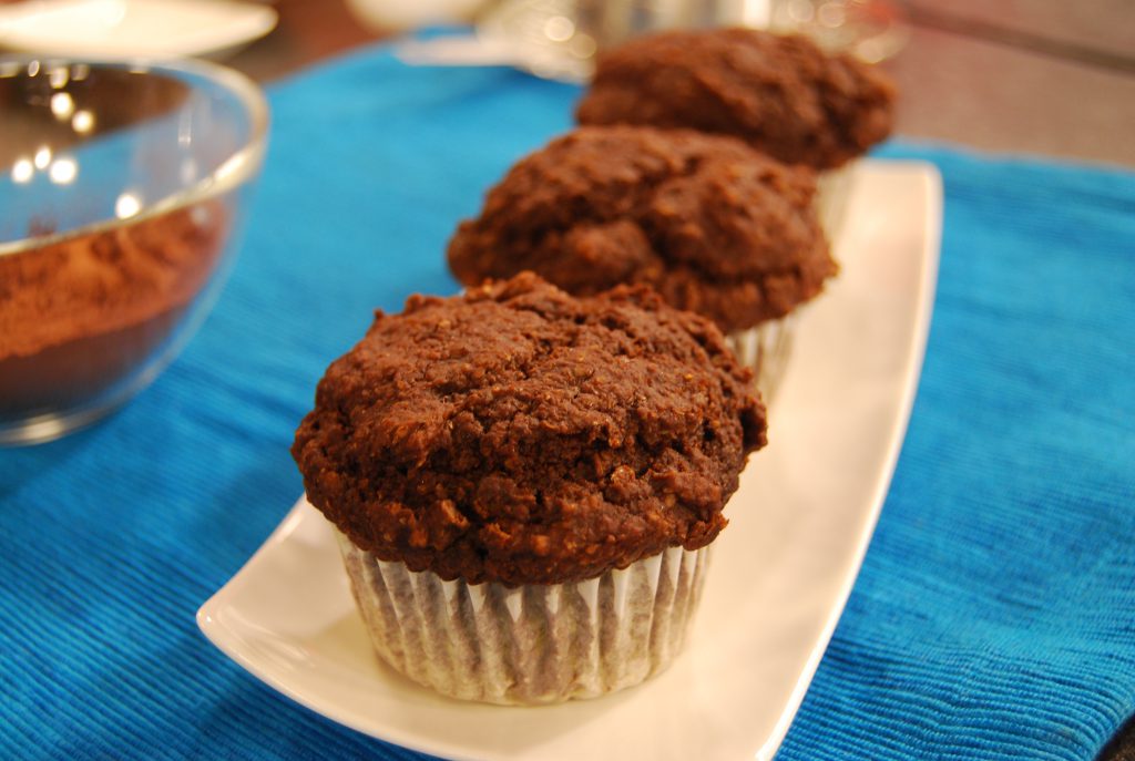 three chocolate muffins sitting on a white plate