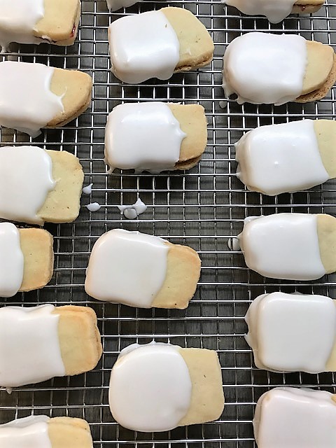 Shortbread Empire cookies on a rack as the almond icing sets