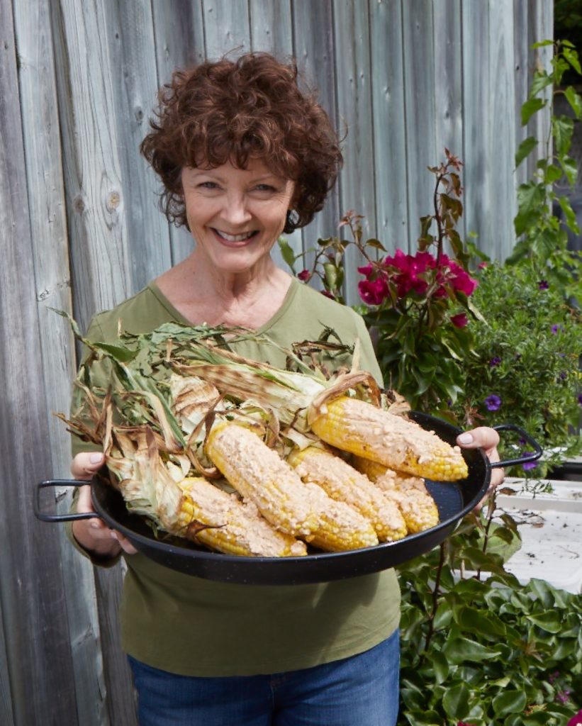 mairlyn is holding a platter of grilled corn